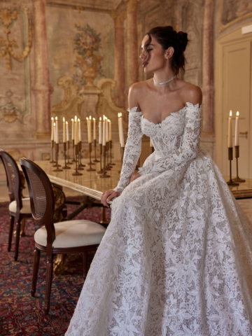Brautkleid Adel seitlich: Die fließende Silhouette mit Allover-Spitze und der raffinierte Herzausschnitt machen dieses Off-Shoulder-Kleid zu einem romantischen Hingucker. Abnehmbare Ärmel sorgen für einen wandelbaren Look.