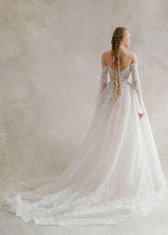 Brautkleid Amber von hinten: Die elegante A-Linie aus französischer Spitze hat eine sanft fallende Schleppe. Der Rücken wird durch die feine Spitze und die abnehmbaren langen Ärmel stilvoll betont.