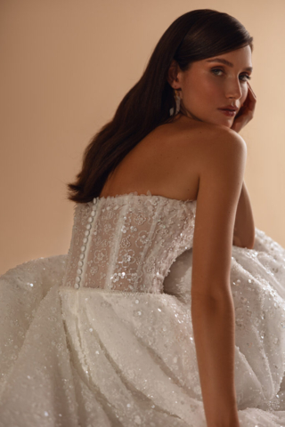 Seitendetail des Brautkleids Eden: Die feine Spitze und Perlenstickereien ziehen sich über das gesamte Kleid. Der gerade Ausschnitt und die dezenten Blumenapplikationen unterstreichen die zarte Eleganz der A-Linie. Knopfleiste am Rücken.