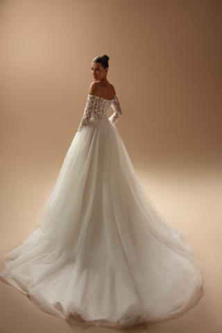 Brautkleid Inaya von hinten: Die A-Linie aus Tüll besticht durch einen cleanen, weit ausgestellten Rock. Die langen Off-Shoulder-Ärmel und der tiefe Rückenausschnitt verleihen dem Kleid eine romantische Note.