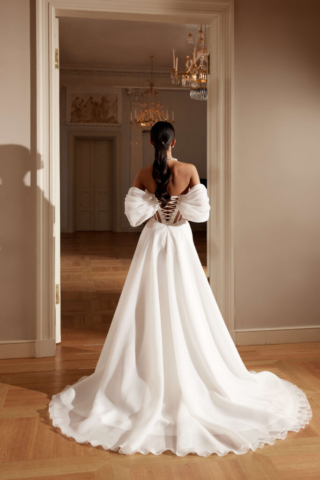 Brautkleid Izabo von hinten: Transparente Einsätze an der Korsage setzen den Rücken stilvoll in Szene. Die fließende A-Linie aus Organza und die leichte Schleppe unterstreichen die schlichte, moderne Eleganz des Kleides.
