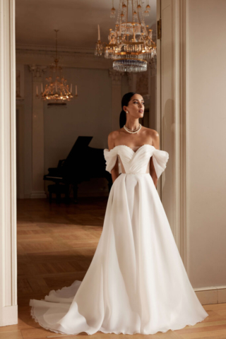 Brautkleid Izabo: Cleane A-Linie aus leichtem Organzastoff mit zarten Carmenärmeln, die das Dekolleté betonen. Der Herzausschnitt verleiht dem Kleid eine romantische Note, während der fließende Stoff für eine luftige Eleganz sorgt
