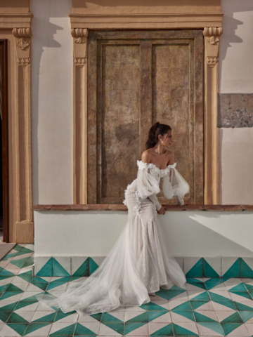 Detail des Brautkleids Polina: Zarte 3D-Applikationen schmücken das Fit-and-Flare-Design. Die abnehmbaren Tüllärmel und Carmenärmel sorgen für einen wandelbaren Look.