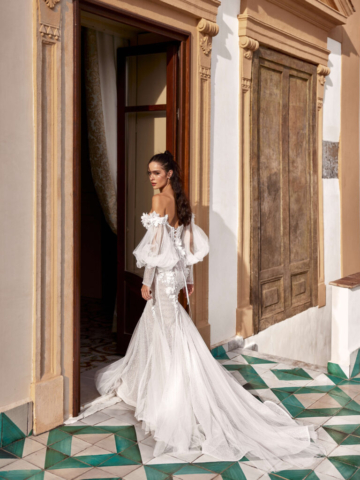 Brautkleid Polina von hinten: Fit-and-Flare-Schnitt mit eleganter Schleppe. Die abnehmbaren Carmenärmel und der leichte Rosé-Unterton verleihen dem Kleid eine romantische Note.