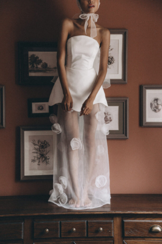 Detail des Brautkleids Pomona: Der Rock des kurzen Satin-Kleids mit gewelltem Saum wird durch den transparenten Unterrock aus Tüll verlängert, was dem Design eine raffinierte Note verleiht.