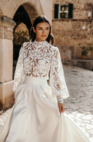 Detail des Brautkleids Rhea: Perlenbesticktes, transparentes Spitzenoberteil mit angedeutetem Rollkragen. Lange, weite Ärmel mit breitem Bund am Handgelenk und feinen Details.