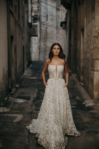 Brautkleid Irma von vorne: Glitzernder Tüll mit bestickten Blumen, A-Linien-Schnitt, gerader Ausschnitt mit schmalem V bis zur Taille und feine Spaghettiträger.
