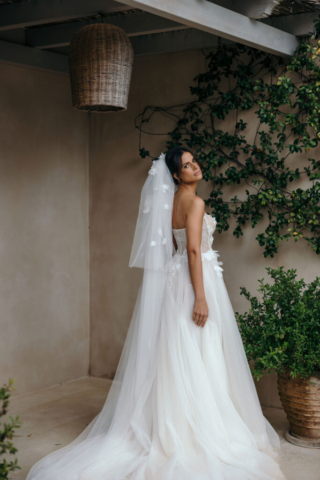 Brautkleid Carlotta seitlich: A-Linie mit glitzernder Korsage und 3D-Applikationen. Der spitz zulaufende Ausschnitt an den Seiten betont die Silhouette und verleiht dem Kleid eine außergewöhnliche Note.